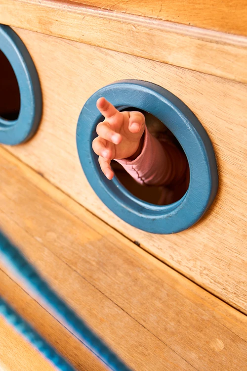 Kinderarztpraxis Strunk Brandis Kind im Boot Kinderhand schaut aus Bullauge raus
